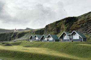 a row of houses on a hill with a lighthouse in the background at Vík Cottages in Vík