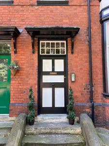 a black door on a brick building with two plants at Stylish Apartment With Secure Parking Close to City in Chester