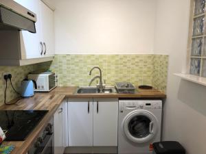 a kitchen with a sink and a washing machine at Stylish Apartment With Secure Parking Close to City in Chester