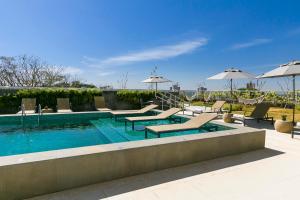 a swimming pool with lounge chairs and umbrellas at Novotel Lencois Paulista in Lençóis Paulista