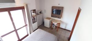 a bedroom with a bed and a table and a tv at Residencial da Praça Garopaba in Garopaba