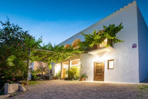 a white house with a wooden door and vines at Villa Near Ibiza Town - San Antonio Sleeps 14 in San Jose