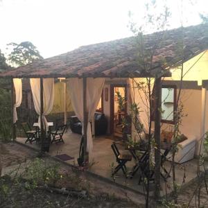 a house with a patio with chairs and curtains at Morada da Águia in Lavras Novas