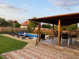 a pavilion with a table and chairs and a pool at Tiszavirág Üdülőház in Kisköre