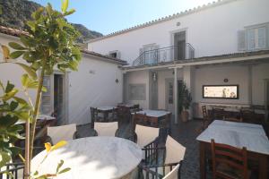 eine Terrasse mit Tischen und Stühlen in einem Gebäude in der Unterkunft Guesthouse Alexandra in Hydra