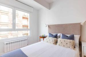 biała sypialnia z dużym łóżkiem i niebieskimi poduszkami w obiekcie New Amara Suite Friends & Families Parking w mieście San Sebastián