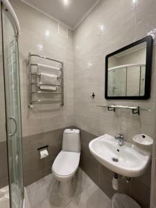 a bathroom with a toilet, sink, and mirror at Gusarskiy Hotel and Apartment in Kyiv