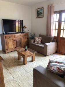 un soggiorno con un divano e una TV di Pouso Bela Vista - Casa de Temporada a Tiradentes