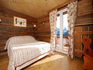 een slaapkamer met een bed en een raam in een hut bij Arc en Ciel in Châtel
