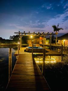 a wooden dock with a bed on the water at night at Pousada Xaxá in Guarda do Embaú