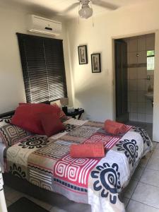 a bedroom with a large bed with red pillows on it at Danamara Garden Studios in Phalaborwa