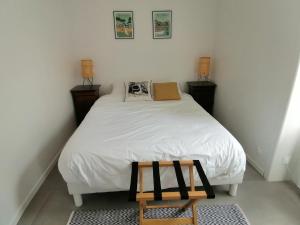 Habitación pequeña con cama blanca y taburete de madera. en Le Chai de Saint-Pierre en Saint-Pierre-dʼOléron