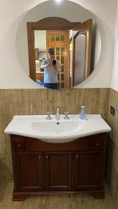 un homme prenant une photo d'un lavabo dans la salle de bains dans l'établissement Casa vacanze villa maresette, à Marsala