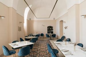 um restaurante com mesas brancas e cadeiras azuis em Villa Pesce 1820 Residenza d'Epoca & SPA em Canosa di Puglia