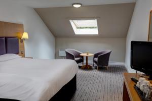 una camera d'albergo con letto, sedie e TV di Orchid Epsom; Sure Hotel Collection by Best Western a Epsom