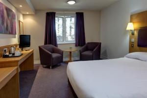 um quarto de hotel com uma cama e duas cadeiras em Orchid Epsom; Sure Hotel Collection by Best Western em Epsom