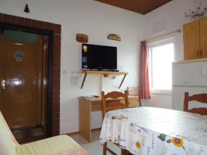 a room with a kitchen with a table and a television at Kod Senke in Komiža