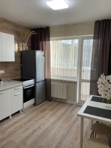 a kitchen with white cabinets and a black refrigerator at PaulMarie Apartments on Kozlova, 1A/2 in Salihorsk
