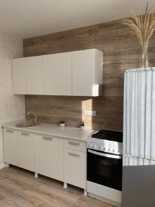 a kitchen with white cabinets and a stove top oven at PaulMarie Apartments on Kozlova, 1A/2 in Salihorsk