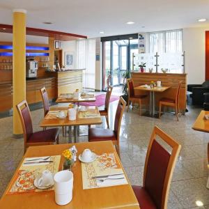 ein Restaurant mit Holztischen und -stühlen und einer Küche in der Unterkunft Hotel Graf Lehndorff zur Messe in München