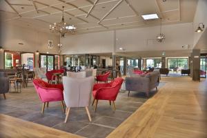 a lobby with chairs and tables and a restaurant at SOWELL HOTELS L'Olivier in Arles