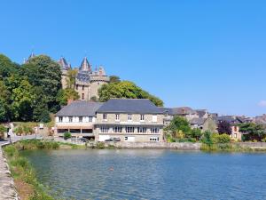 a large building next to a river with a building at Hôtel Restaurant du Lac in Combourg