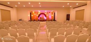 a banquet hall with white chairs and a stage at GG HOTELS in Tiruppūr