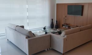 a living room with two couches and a table at Em Capao da Canoa - Luxo e conforto com praia , sol e mar em Capão. in Capão da Canoa