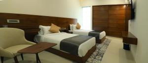 a hotel room with two beds and a chair at GG HOTELS in Tiruppūr +29 photos