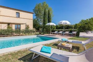 einen Pool mit Stühlen und Sonnenschirmen neben einem Haus in der Unterkunft Bibbianello in Buonconvento