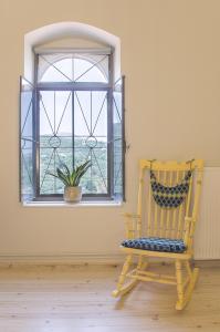 una sedia a dondolo davanti a una finestra con una pianta di Αρχοντικό στα Τοπόλια a Kaláthenai