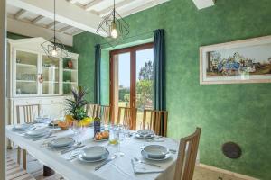 ein Esszimmer mit einem weißen Tisch und grünen Wänden in der Unterkunft Bibbianello in Buonconvento