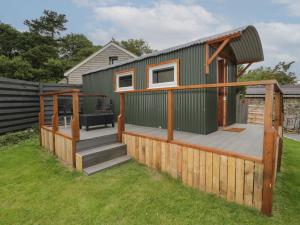 ein kleines grünes Haus mit einer Terrasse und einer Treppe in der Unterkunft Glyder Fach in Bangor