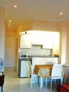 a kitchen with white cabinets and a table and chairs at Studio Croisette in Cannes