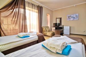una habitación de hotel con 2 camas y una silla en Rasputin Hotel, en Mostovskoy
