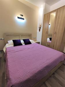 a bedroom with a large bed with a purple comforter at Villa Pavlina in Ixia