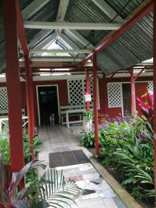 a patio with a red building with a roof at Hospedaje Meryscar in Tortuguero