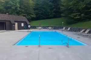 a large blue swimming pool with chairs around it at Waitsfield Condo with Pool and On-Site Trail Access! in Waitsfield