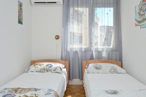 dwa łóżka ustawione w pokoju z oknem w obiekcie Apartman Lazy Summer Days w Splicie