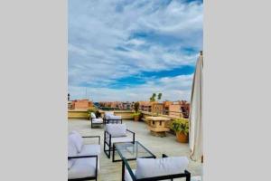 a balcony with chairs and tables and a cloudy sky at LUXURY APARTMENT IN THE HEART OF MARRAKECH GUELIZ in Marrakech