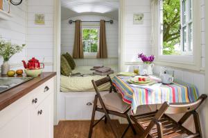 una cocina con mesa y sillas en una casa pequeña en Romantic Shepherds Hut, Kenilworth en Kenilworth