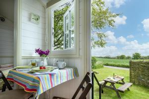 a table on a porch with a view of a yard at Romantic Shepherds Hut, Kenilworth in Kenilworth