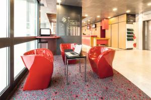 a lobby with red chairs and a laptop on a table at Ibis Roma Fiera in Rome