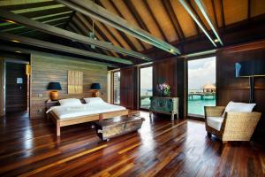 Gangehi Island Resort & Spa في غانغيهي: غرفة نوم بسرير في غرفة ذات أرضيات خشبية