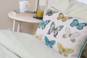 a pillow with butterflies on it next to a table at The Cow Shed, Kenilworth, Sleeps 2 in Kenilworth