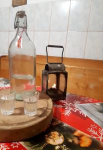 a bottle of water and two glasses on a table at Cabana Colnic in Măgura