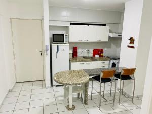 cocina con mesa, sillas y nevera en Quarto e sala com piscina próximo à praia, en Maceió