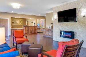 a lobby with chairs and a fireplace with a flat screen tv at Comfort Inn Auburn - Seattle in Auburn