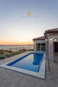 a swimming pool in front of a house at Vista Villas - Sweet Life Apartment Villa S in Ražanac