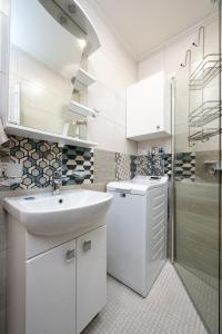 a white bathroom with a sink and a washing machine at Brand new, cozy downtown apartment near airport and bus station. in Tallinn